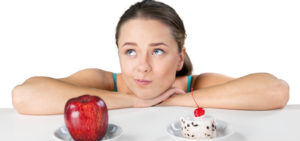 woman deciding between an apple or cake